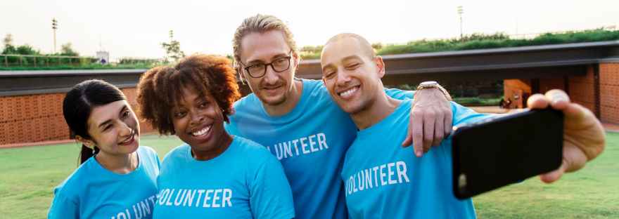 four person taking selfie while wearing blue volunteer t shirt
